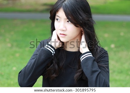 Portrait of thai student teen beautiful girl Black Dresses relax in park.
