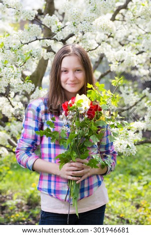 smiling teen girl with the bouquet of spring flowers at the blooming garden
