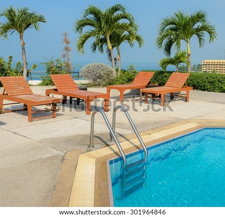 Swimming pool with wooden sun loungers with sea background