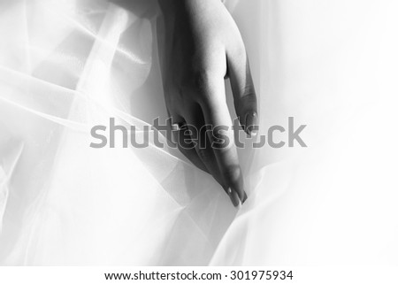 Closeup of female hand with beautiful wedding ring from precious metal on haze fabric of bridal dress black and white, horizontal picture
