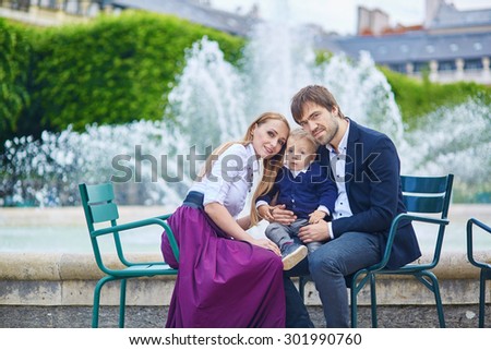 Happy family of three in the beautiful garden in Paris