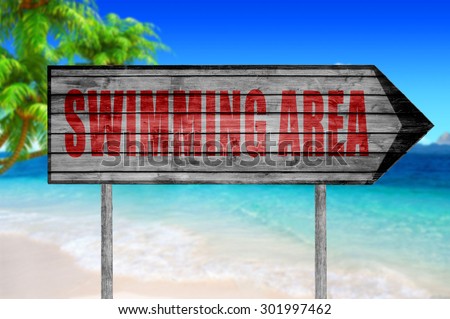 Red Beach Swimming Area wooden sign with a beach on background