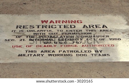 A restricted area warning sign on ground at a US Airforce base.