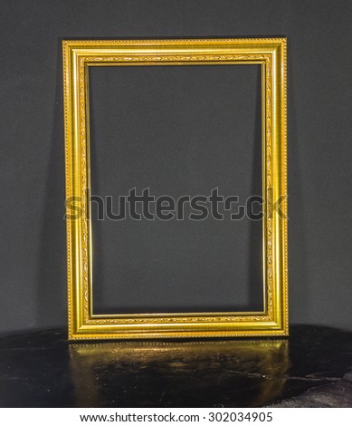 Gold vintage picture frame on wood and on black background.