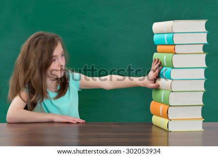 Portrait Of Girl Touching Multi-colored Stack Of Books At The Table