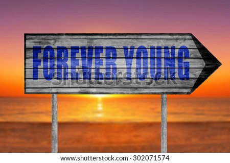 Forever Young wooden sign with on beach background