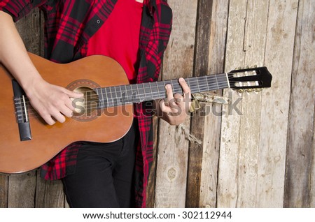 Young man playing acoustic guitar, vintage barn door in the background