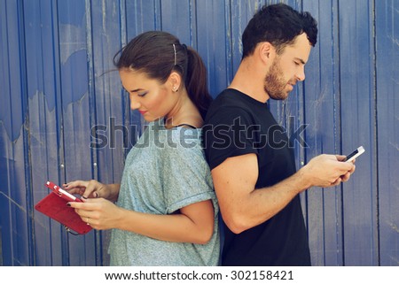 Young couple taking using smartphones. Selfie, social networks, internet addiction, love, friendship, young adult, leisure concept. Image toned and noise added.