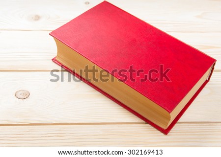 Red book on wooden table. Back to school. Copy space