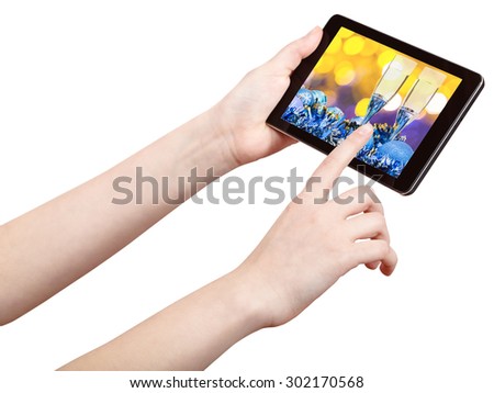 hand touches tablet pc with Christmas still life on screen isolated on white background