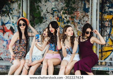Five beautiful young girls make selfie at the bus stop