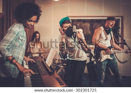 Multiracial music band performing in a recording studio  Royalty-Free Stock Photo #302301725