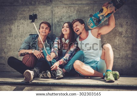 Cheerful friends with with skateboard taking selfie outdoors Royalty-Free Stock Photo #302303165