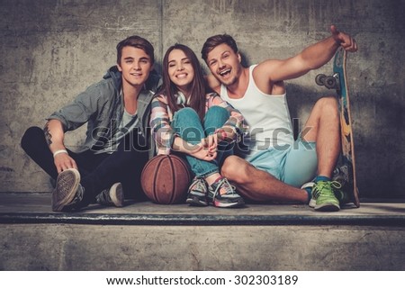 Cheerful friends with with skateboard and ball outdoors