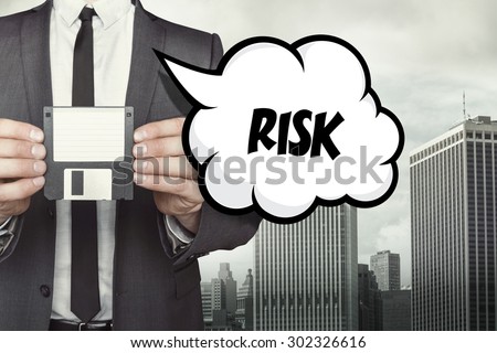 Risk text on speech bubble with businessman holding diskette on cityscape background