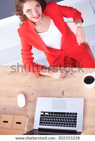 Attractive woman sitting at desk in office, working with laptop 