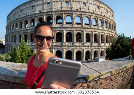 Woman with her smartphone in front of the colosseum in roma