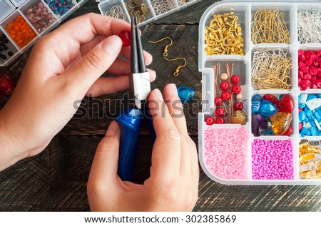 Making of handmade jewellery. Box with beads and glass hearts on old wooden background. Handmade accessories. Top view Royalty-Free Stock Photo #302385869