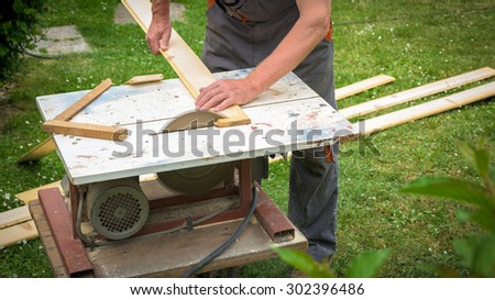 Carpenter working with electric buzz saw cutting wooden boards