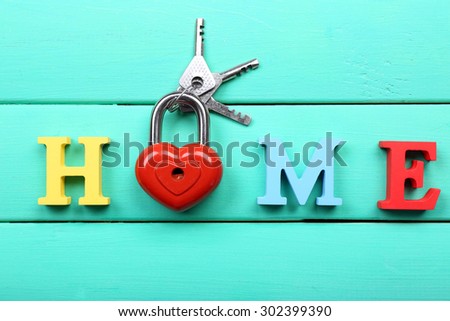 Decorative letters forming word HOME with lock and keys on wooden background
