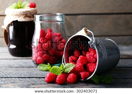 Sweet raspberries in decorative bucket on wooden  background