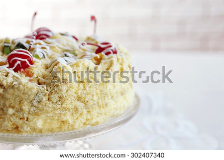 Butter cake with cherries on stand, on light background
