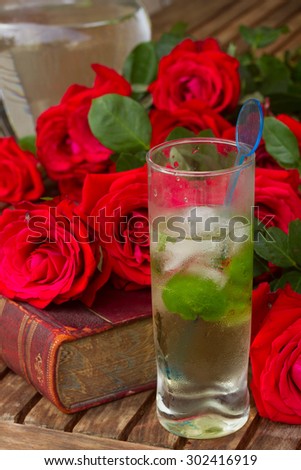  vintage old book  on table with roses and long drink