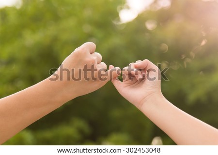 Mother and daughter making a pinkie promise on nature background Royalty-Free Stock Photo #302453048