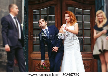 stylish luxury red haired bride and elegant groom, throwing candies, wedding ceremony on the background of the old church