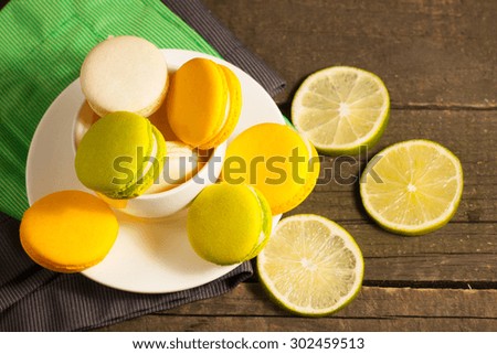 A set of white coffee cup with yellow and green macarons on a rustic wooden background