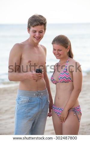 A picture of a young couple using  smart phone at the beach