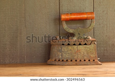 It is Old charcoal Iron on wooden table with wooden background.