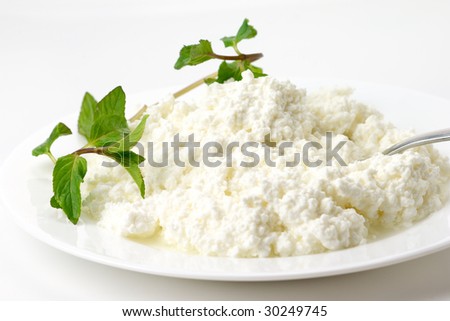Cottage cheese with mint in white plate on light background.