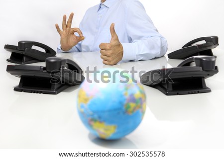 globe and like hand with office phones on desk, global international support concept