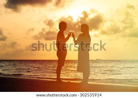 Silhouette of couple drinking wine at sunset beach, romantic beach vacation