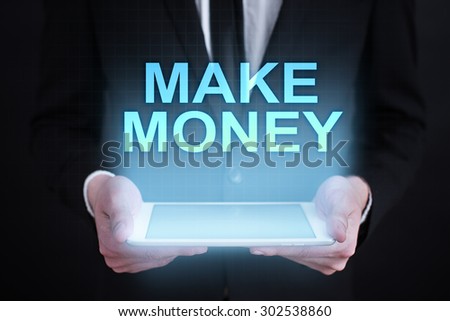 Businessman holding a tablet pc with "make money" text on virtual screen. Business concept. Internet concept.