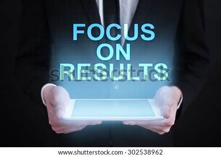Businessman holding a tablet pc with "focus on results" text on virtual screen. Business concept. Internet concept.