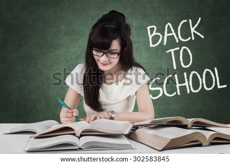 Portrait of female high school student back to school and doing her task on the table with books
