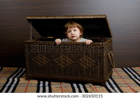 photo of beautiful little girl sitting in suitcase 