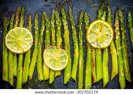 baked asparagus with lemon on a dark background Royalty-Free Stock Photo #302702174