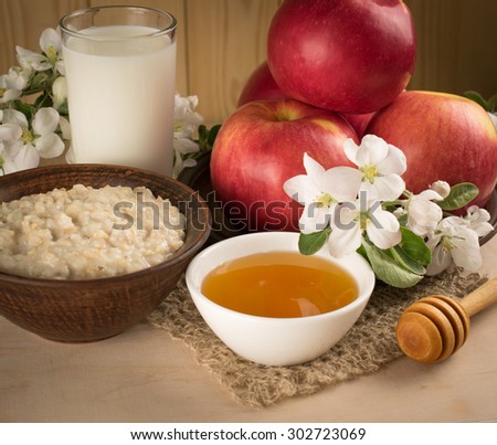 Red apples with oatmeal, milk and honey, twig flowers on the background of wooden wall. For this photo applied vignetting effect.