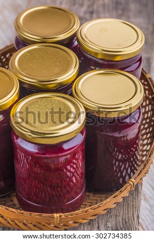 Jars of jam with fresh cherries in old basket