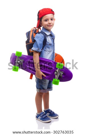 Portrait of a school kid holding a skateboard and a basketball on white background