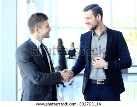 businesss and office concept - two businessmen shaking hands in office Royalty-Free Stock Photo #302765114