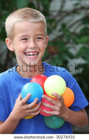 Happy laughing young boy playing with colored balls in his hands