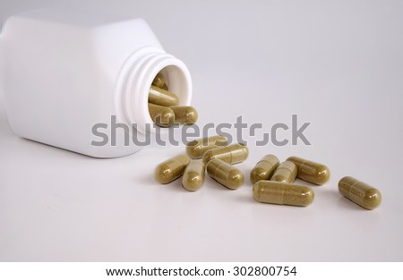 Herb pills spilled out of an opened bottle