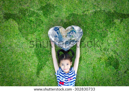 World heart day concept and well being health care campaign with smiling happy kid on eco friendly green lawn. Elements of this image furnished by NASA Royalty-Free Stock Photo #302830733
