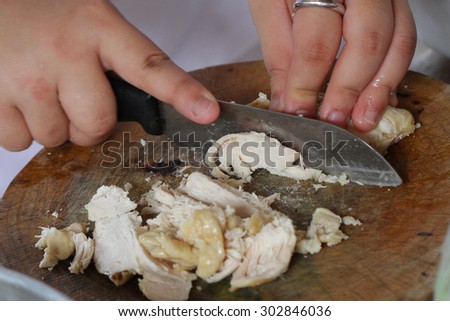 Chef slicing grilled chicken in kitchen