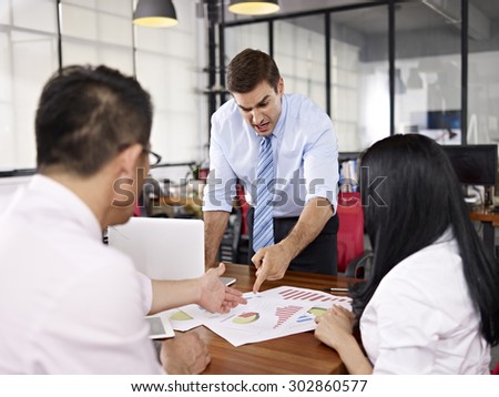 two asian business executives arguing with caucasian superior in office of a multinational company. Royalty-Free Stock Photo #302860577