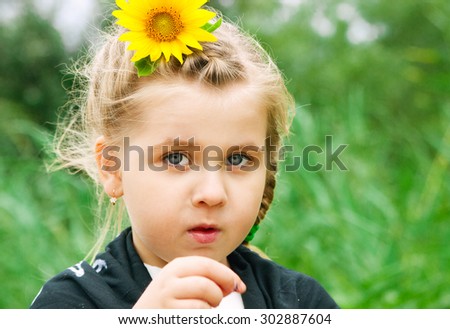 blonde girl with a sunflower in her hair has a surprised look